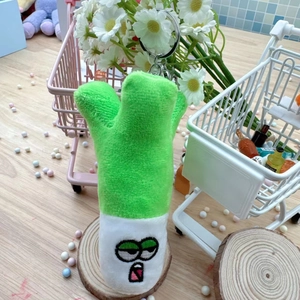 Close-up of funny green leek plush keychain with cute embroidery and metal ring