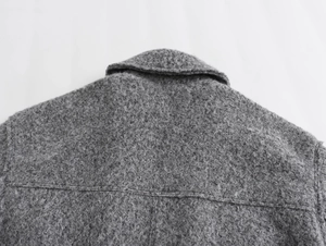 Détail du col arrière et de l'épaule sur une veste grise en texture de laine bouclée
