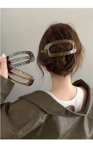 Vue détaillée de pinces à cheveux ovales en acétate vert olive et ambre sur cheveux