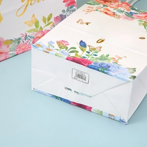 Detail view of floral paper gift bag base showing size 21x15x8cm and barcode specs