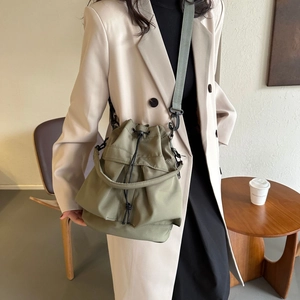 Sac seau en nylon vert armée avec cordon et bandoulière réglable porté par un mannequin