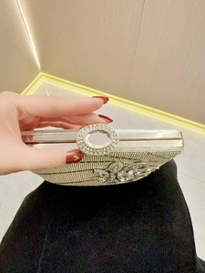 Detailed view of silver evening clutch bag featuring floral crystal applique and oval buckle