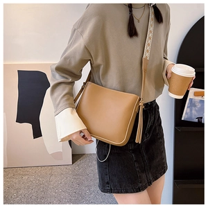 Brown vintage small tote bag with geometric wide strap and tassel detail shown with model
