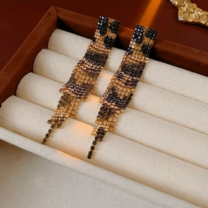 Detailed view of leopard print tassel earrings with inlaid diamonds in a velvet box