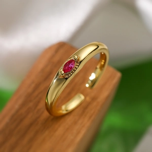 Macro detail of gold-plated ring with red marquise zircon on a wooden stand
