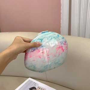 Macro detail of oval marble pattern clutch showing glossy gradient finish and texture