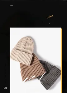 Detail of knitted beanies in beige, camel and grey with ribbed texture and folded brim
