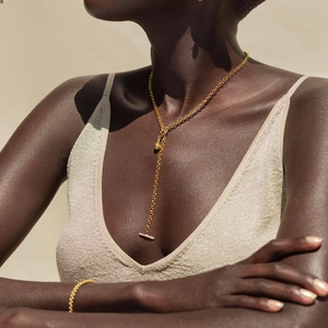 Detailed view of gold OT buckle water drop necklace and bracelet on a female model