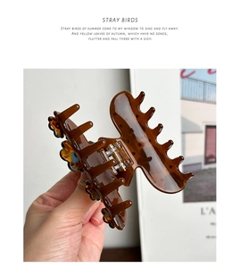 Detailed macro view of a brown tortoise shell flower hair claw clip with crystal accents