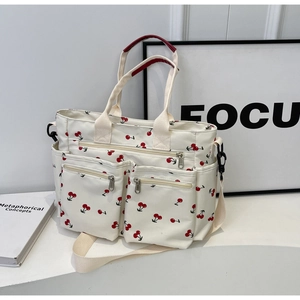 Detail of printed tote bag with cherry pattern and functional front zipper pockets