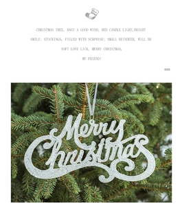 Macro detail of Merry Christmas glitter lettering ornament hanging on pine tree branch