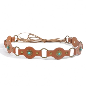 Detailed macro view of vintage brown leather waist belt with turquoise stones and brass rings