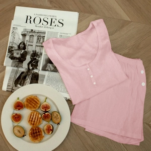 Detailed flat lay of pink ribbed knit pajama set with buttons on a wooden background