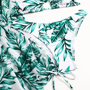 Detail of green tropical palm leaf print on white bikini bottoms and sheer mesh cover-up