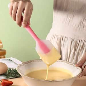 Pink silicone spatula mixing yellow batter in a bowl for DIY cake baking and dessert prep