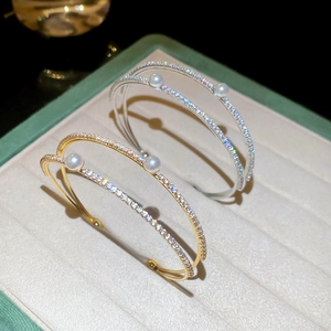 Detail of gold and silver double-layered bangles with sparkling cubic zirconia and pearls