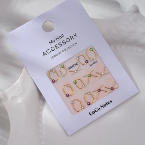 Détail de bijoux d'ongles dorés avec strass sur emballage blanc pour manucure DIY