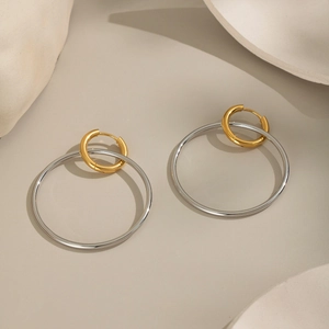 Zweifarbige Edelstahl-Ohrringe in Gold und Silber auf beigem Hintergrund liegend