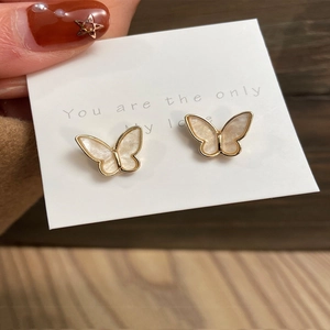 Detail view of golden butterfly earrings with white mother-of-pearl inlay and stud backings