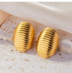 Macro detail of gold-plated oval stud earrings with elegant horizontal textured lines