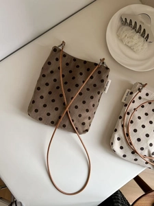 Polka dot corduroy crossbody bags in beige and khaki with leather straps on a white table