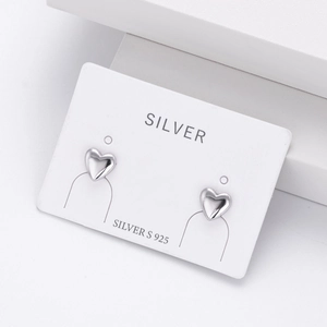 Macro detail of glossy S925 sterling silver heart studs on a professional display card