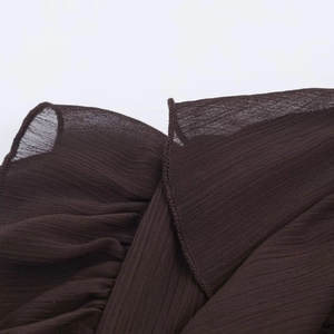 Close-up of deep brown chiffon fabric showing fine pleated texture and stitching quality
