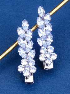 Detailed macro view of silver flower earrings with sparkling cubic zirconia on blue texture