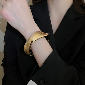 Vue rapprochée d'un bracelet doré irrégulier avec une finition miroir polie au poignet