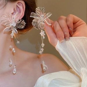 Close-up of transparent flower tassel earrings with crystals on a female model