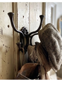 Detail of vintage black cast iron multi-hook rack mounted on a rustic wooden door