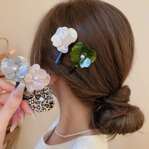 Vue détaillée de barrettes fleurs en acétate avec perles et strass portées sur les cheveux