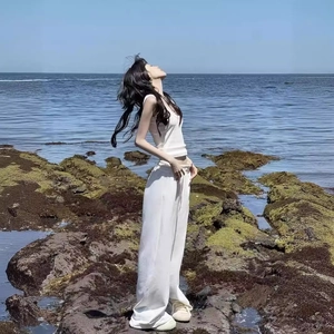 Detail of white cotton wide-leg trousers and tank top set against seaside background