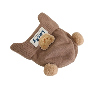 Brown knit winter hat for kids with plush bear patch and dual pom-poms on white background