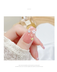 Close-up of hand wearing 3D resin floral nail charms in various colors on long nails