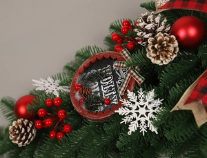 Gros plan d'une plaque Holly Jolly sur un feston de Noël avec des pommes de pin et baies
