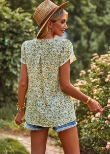 Rear view of floral short-sleeved V-neck top with lace trim in a garden setting