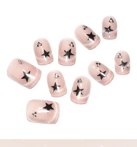 Detail of 10-piece short nude pink cat-eye press-on nails with black stars and rhinestones