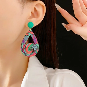 Détail rapproché des boucles d'oreilles bohèmes en forme de goutte aux motifs abstraits