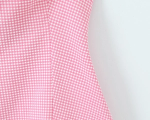 Close-up of pink and white gingham fabric texture and stitching of the halter neck top