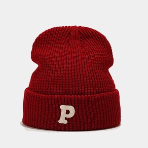 Detail of dark red knit beanie showing thick texture and white letter P embroidery