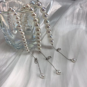 Detail of aurora pearl bracelet on glass with white silk fabric and adjustable silver chain