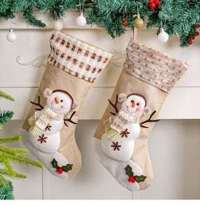 Dettaglio di calze natalizie beige con pupazzo di neve 3D in peluche e decorazione di agrifoglio