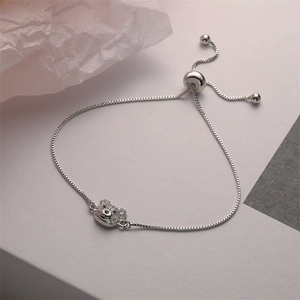 Adjustable silver bear bracelet with cubic zirconia paving on textured background