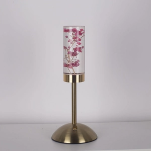 Detail of pink preserved flowers inside a clear cylinder lamp with brass base