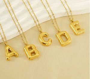 Détail des pendentifs lettres A à E dorés style bulle avec finition métal poli