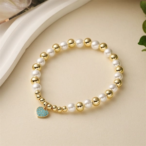 Bracelet élégant de perles dorées et nacrées avec un pendentif en cœur de zircon bleu