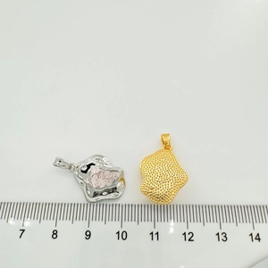 Detailed comparison of pink crystal and gold hammered charms beside a measuring ruler