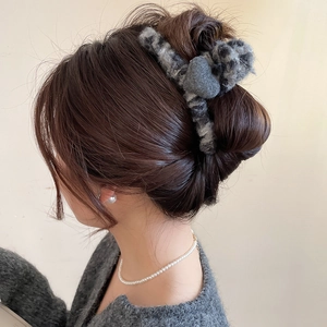 Détail d'une grande pince à cheveux cœur floquée grise sur un chignon bas