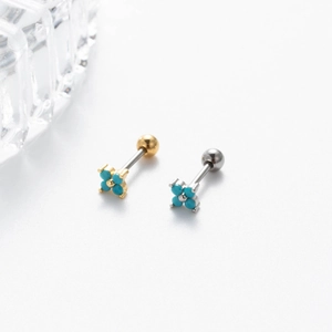 Macro shot of gold and silver four-leaf clover earrings with blue stones and screw ball backs